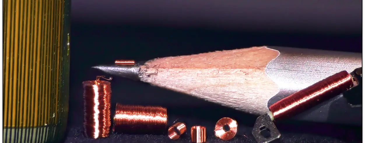 Copper microcoils of several shapes beside the sharpened tip of a pencil